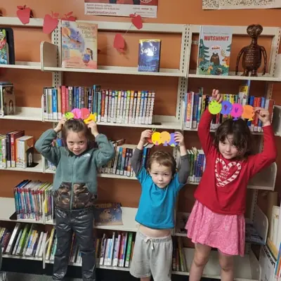 three children holding crafts above their heads